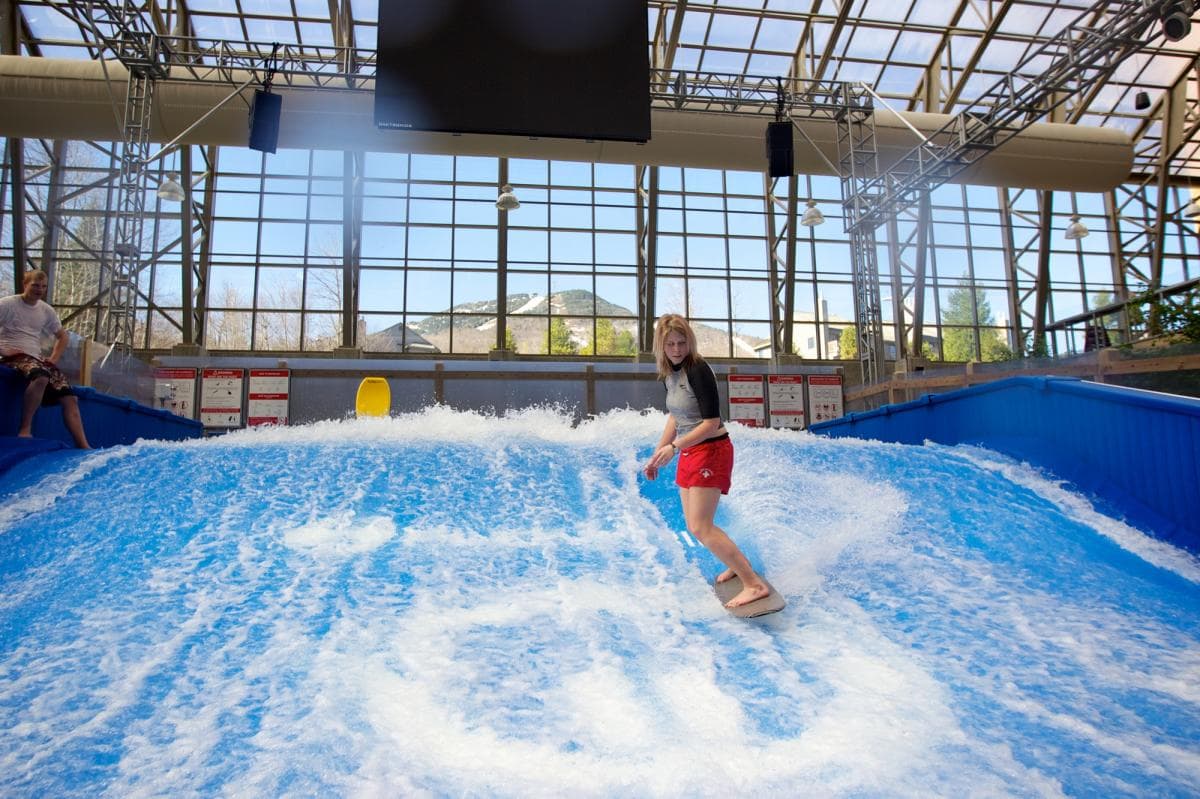 A person rides a wave on a flowboarding simulator indoors. A person rides a wave on a flowboarding simulator indoors.