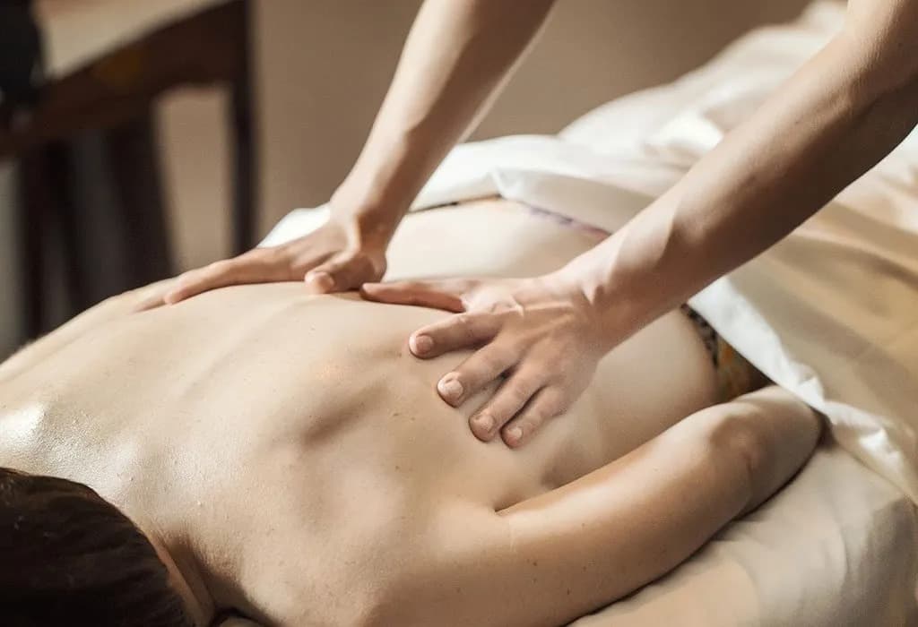 A person receives a back massage on a spa table.