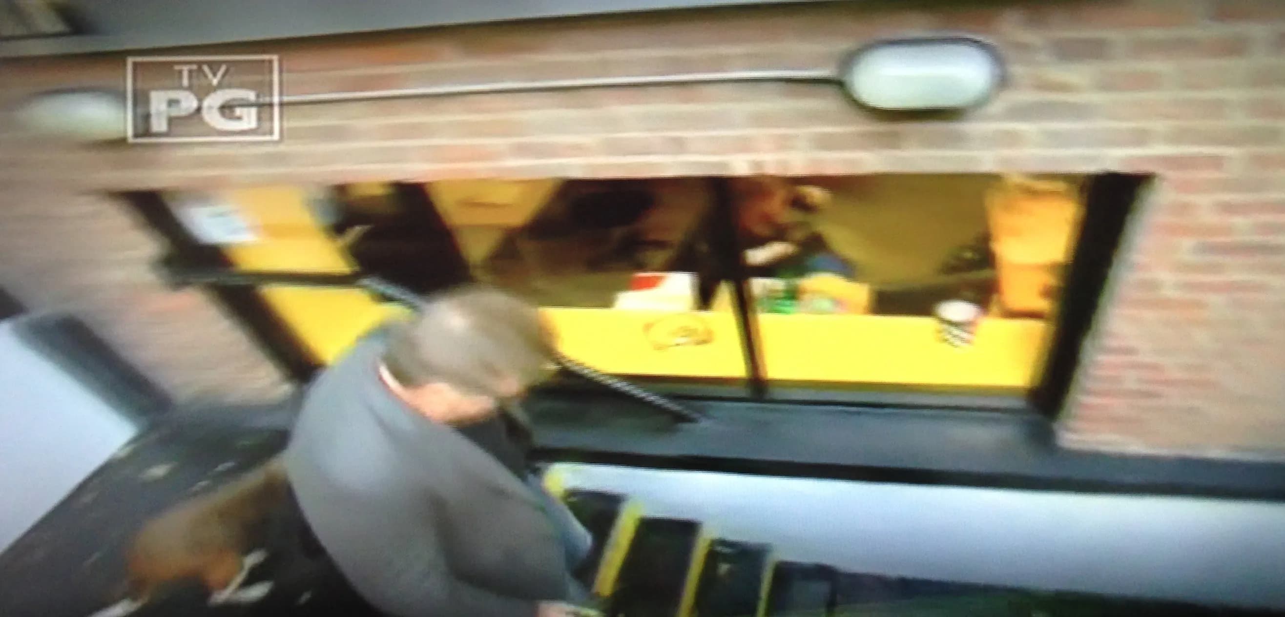 A man descends stairs outside a building with large yellow windows.