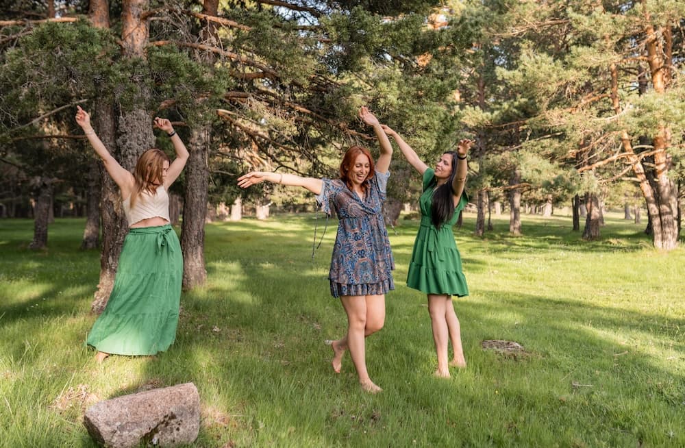 Three women joyfully dancing in a grassy forest clearing. Three women joyfully dancing in a grassy forest clearing.