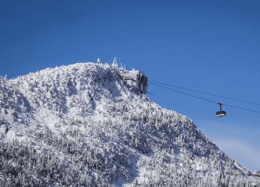 A snow-covered mountain peak with a gondola and ski station against a clear blue sky. A snow-covered mountain peak with a gondola and ski station against a clear blue sky.