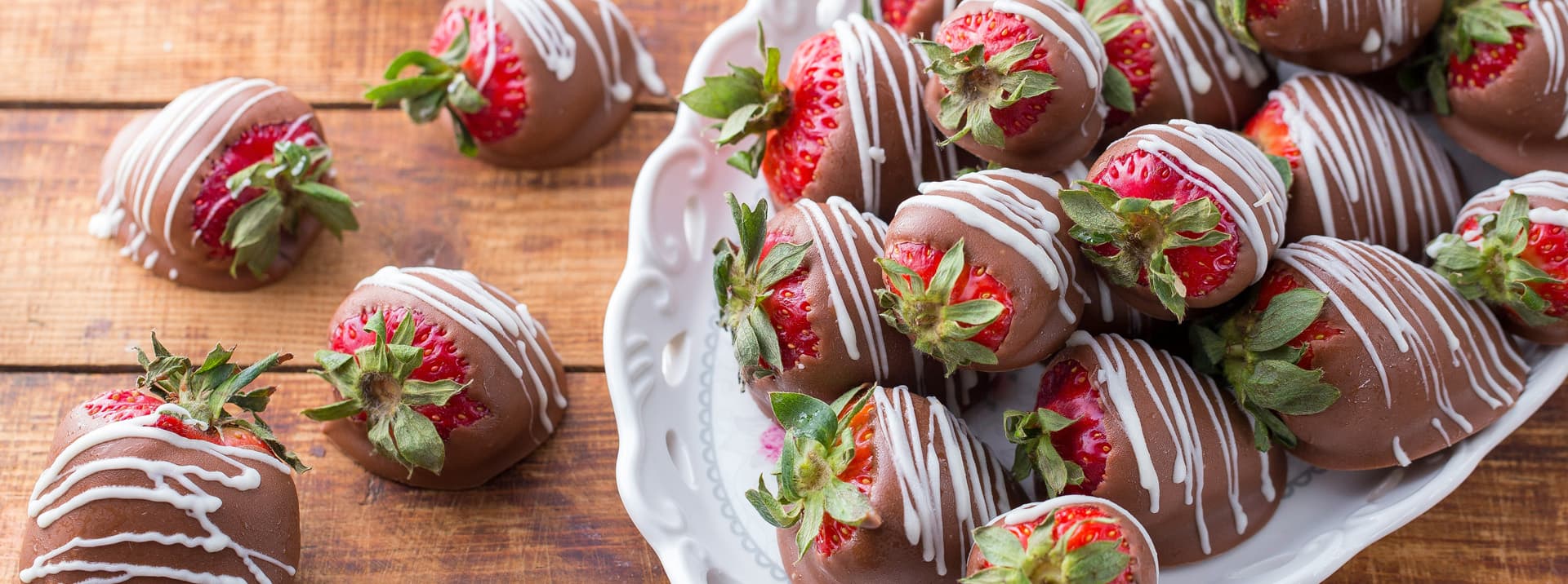 A plate of chocolate-covered strawberries drizzled with white chocolate.