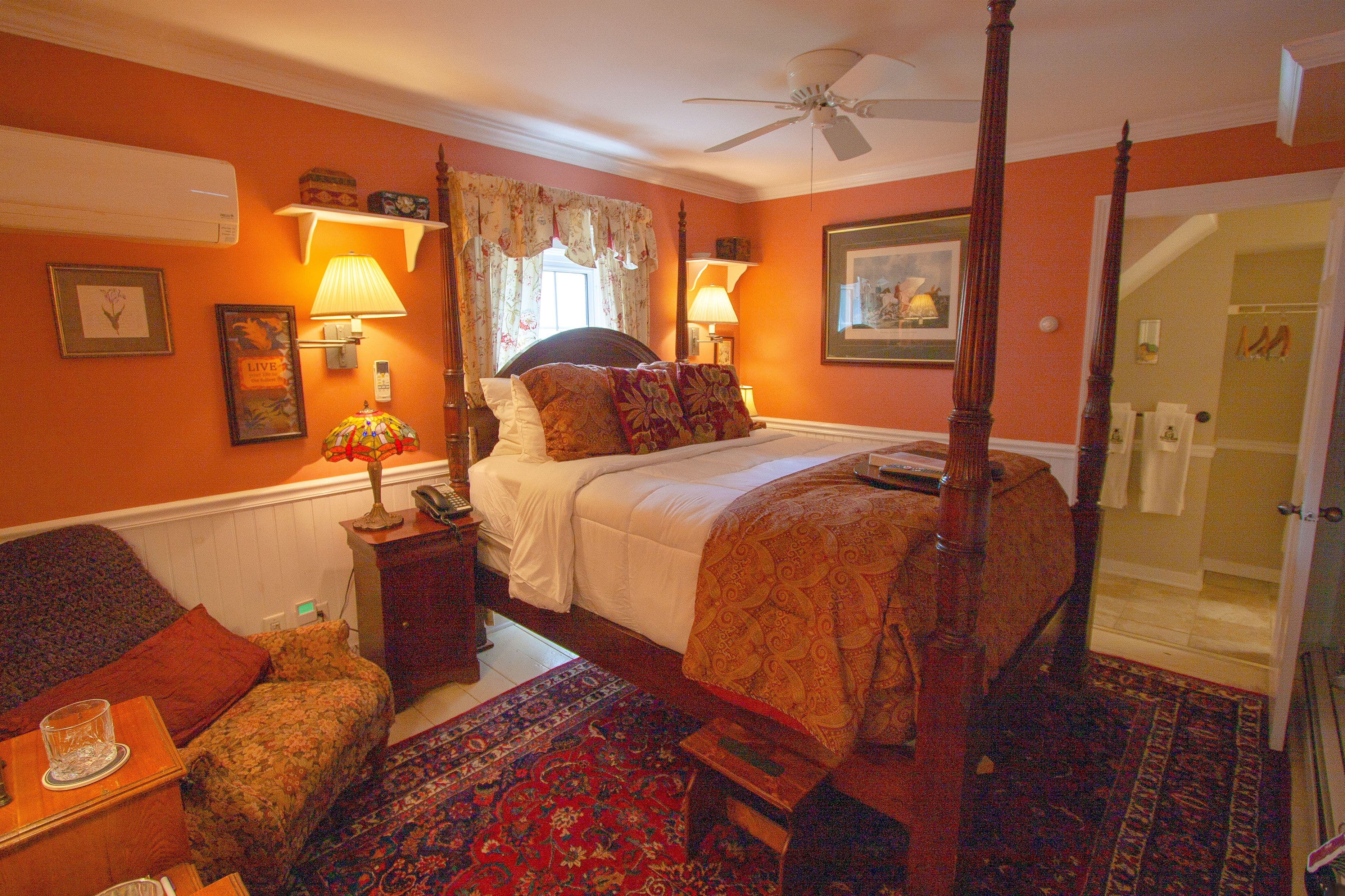 Cozy bedroom with a four-poster bed, warm orange walls, and plush furnishings. Cozy bedroom with a four-poster bed, warm orange walls, and plush furnishings.