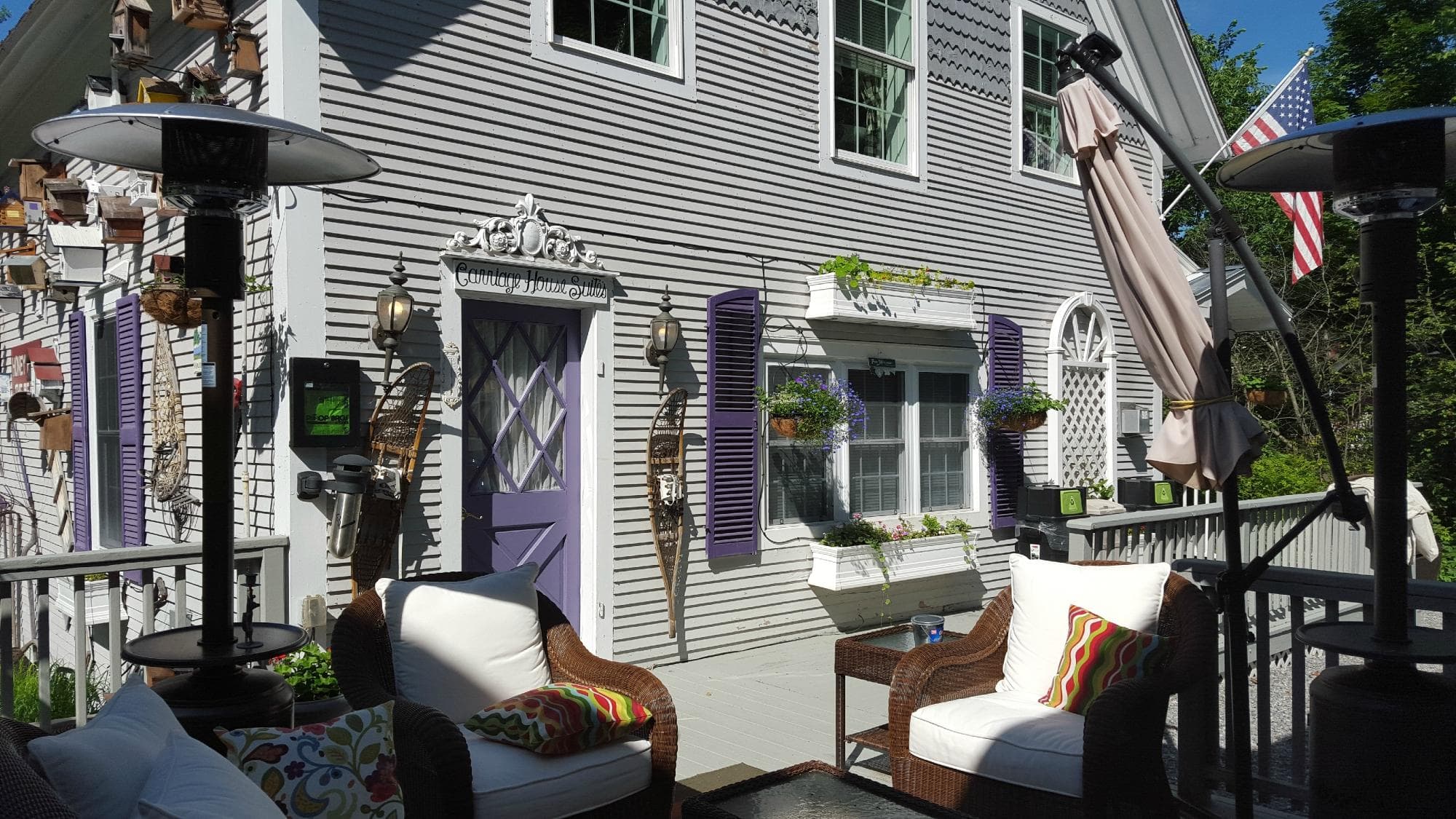 A charming house with purple shutters and comfortable outdoor seating.