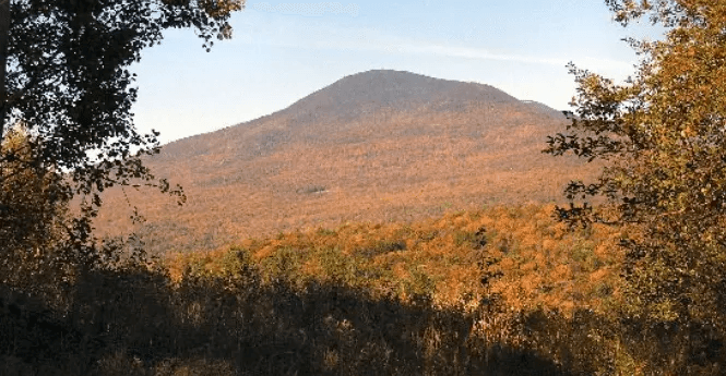 A panoramic view of a mountain surrounded by vibrant autumn foliage.
